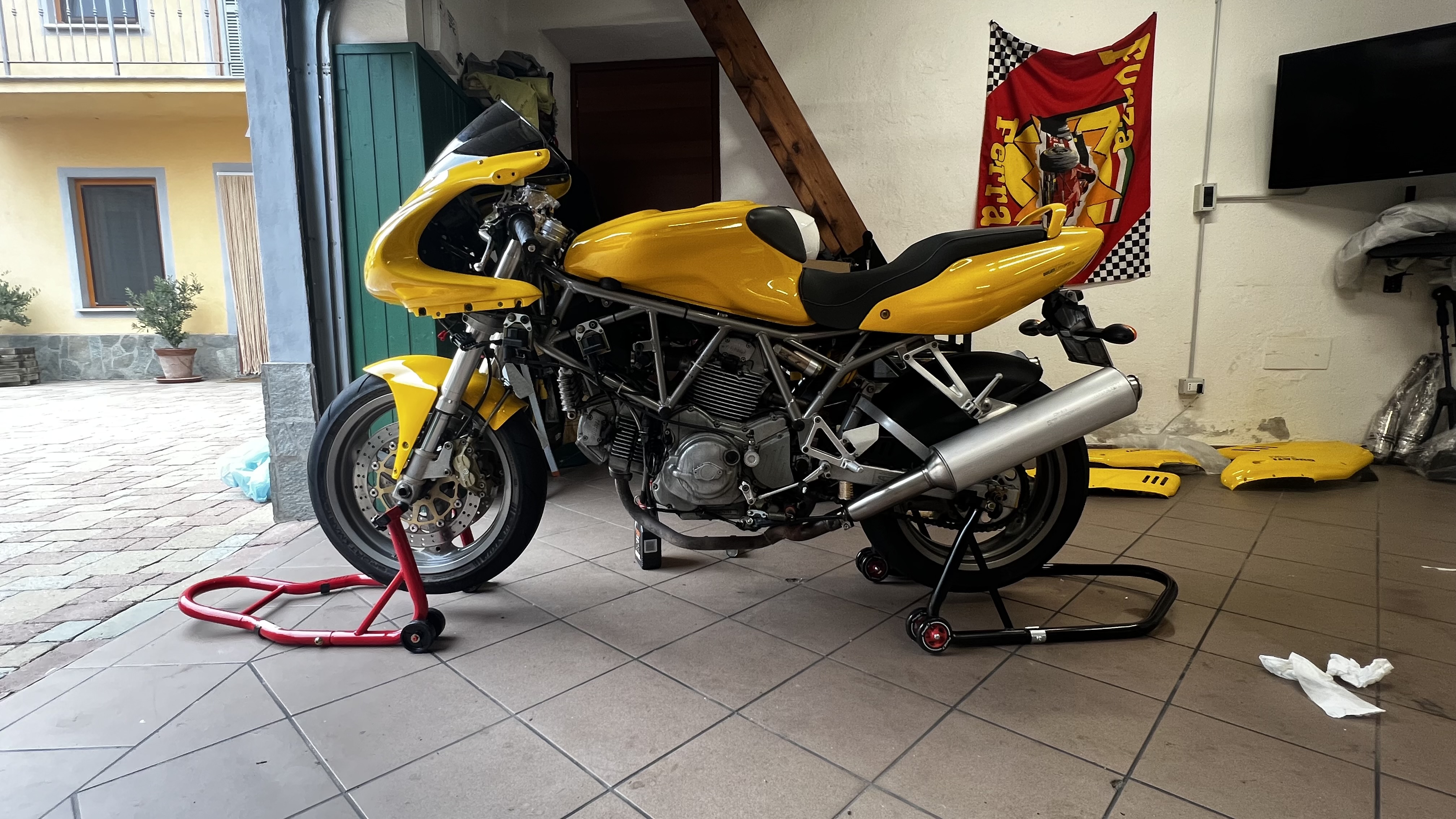 Yellow Ducati 750 SS on paddock stands in the garage