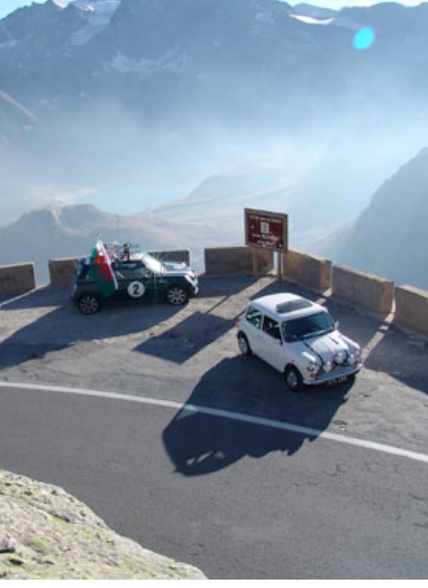 Two classic Minis parked at the Colle del Nivolet hairpin above Ceresole Reale, an Italian Job filming location in the Italian Alps